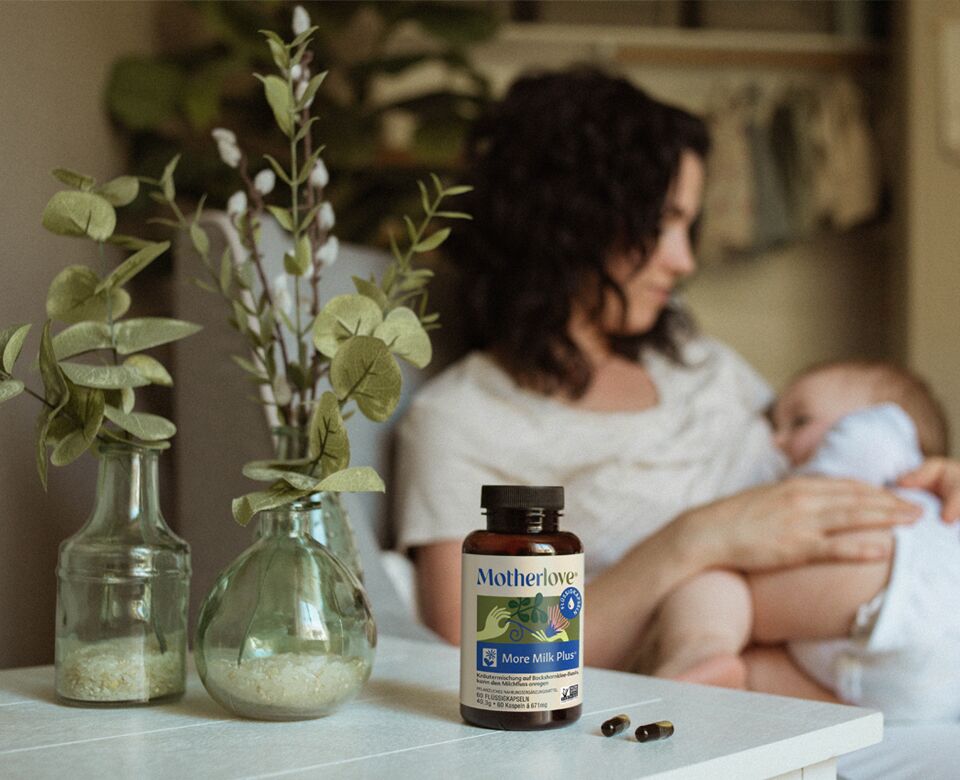 Motherlove More Milk Plus Kapseln liegen auf Beistelltisch neben stillender Mutter