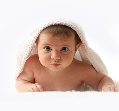 Baby peeks out from under a white blanket