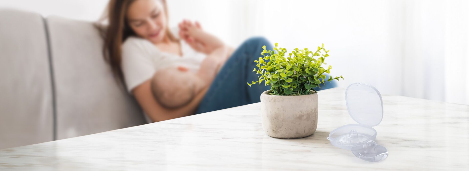 Mutter stillt ihr Baby, auf dem Tisch stehen die Stillhüchen bereit